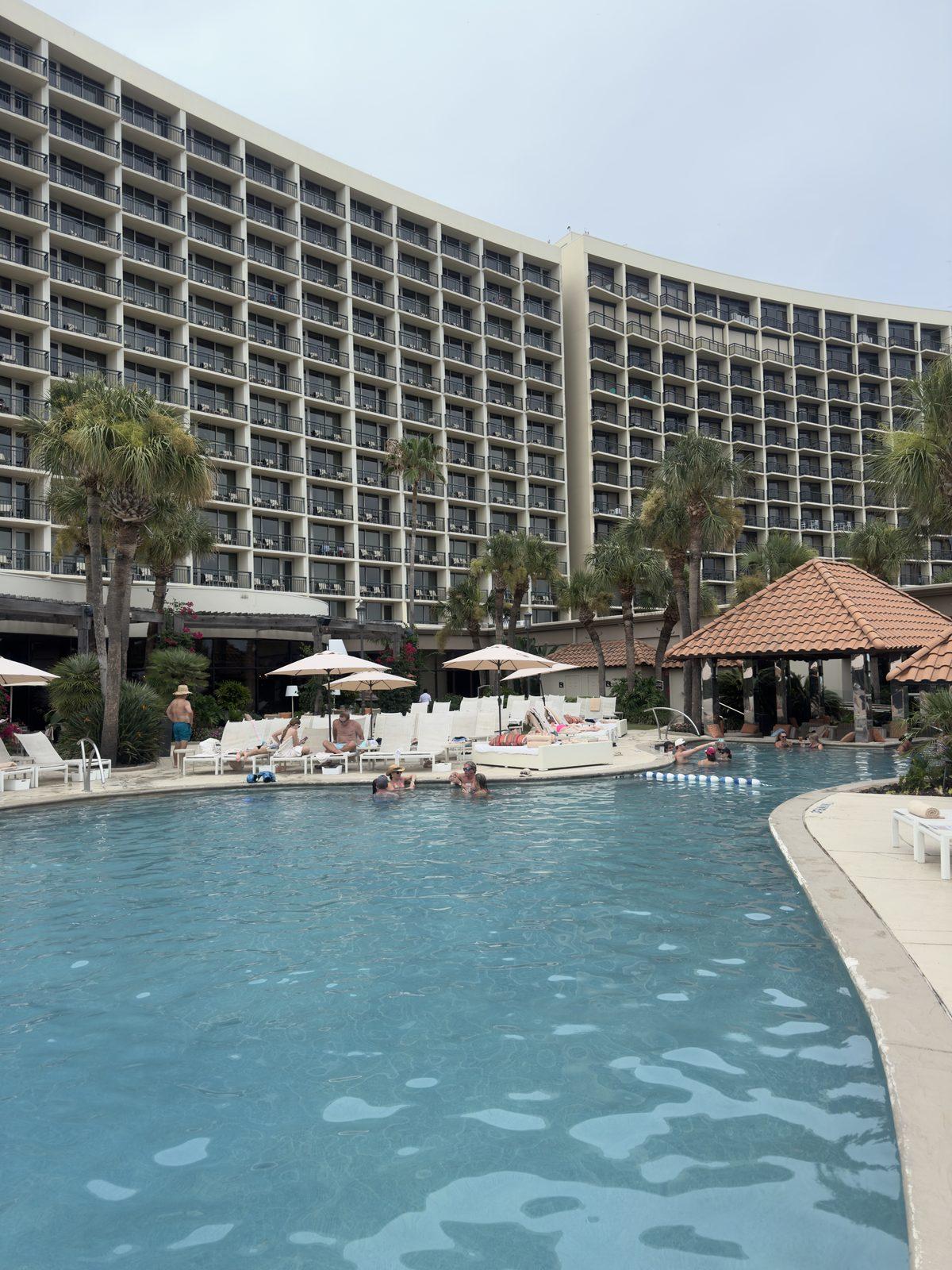 The wide resort pool curving around a Gulf Coast hotel