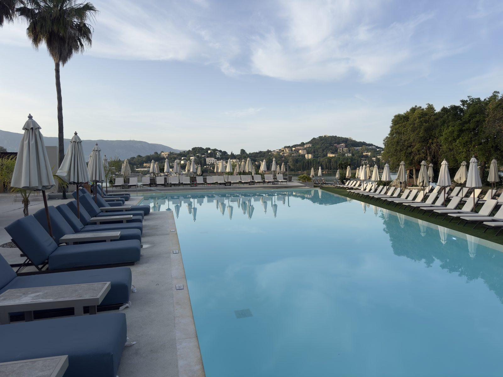 A long resort pool lined with sun loungers and umbrellas
