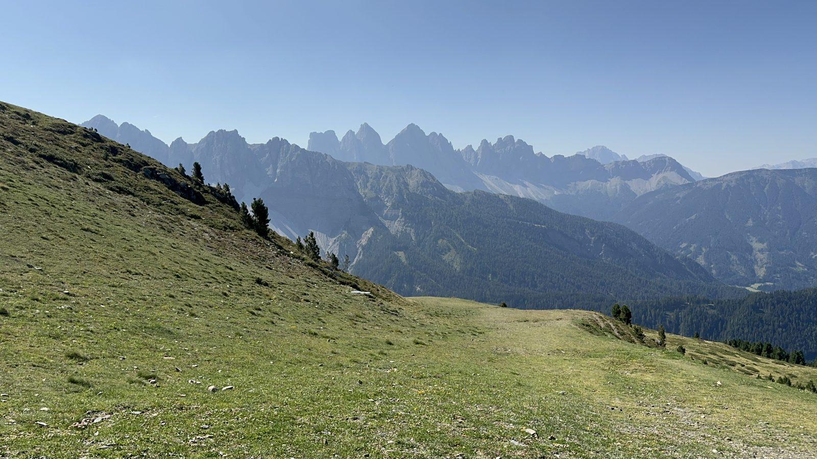 An alpine meadow falling away to the valley, Dolomite peaks on the horizon
