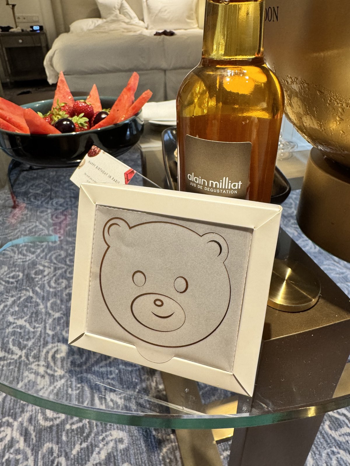 A bottle of juice and a bear-shaped card holder on a hotel room table